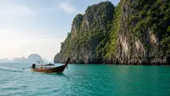 Long-tail boat approaching Railay limestone cliffs in Krabi